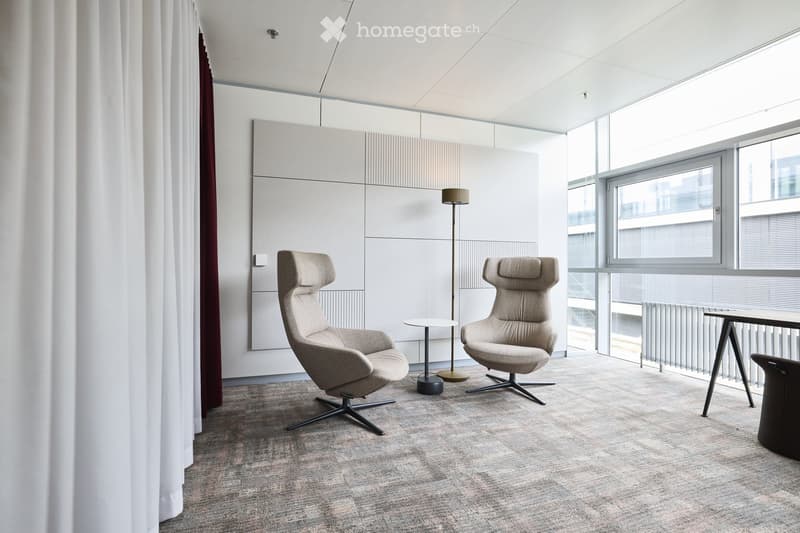 Furnished Room. Modern living room with two beige armchairs, a small round table, and a floor lamp, featuring large windows and a neutral color palette.