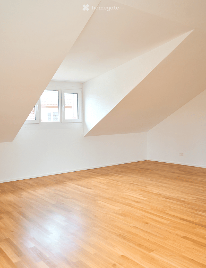 Unfurnished Room. Empty room with wooden flooring, white walls, and a slanted ceiling. Two windows are visible on one wall.