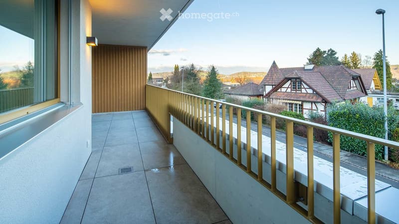 Balcony / Terrace. Modern balcony with tiled floor, wooden railing, large window, and scenic view of houses and trees.