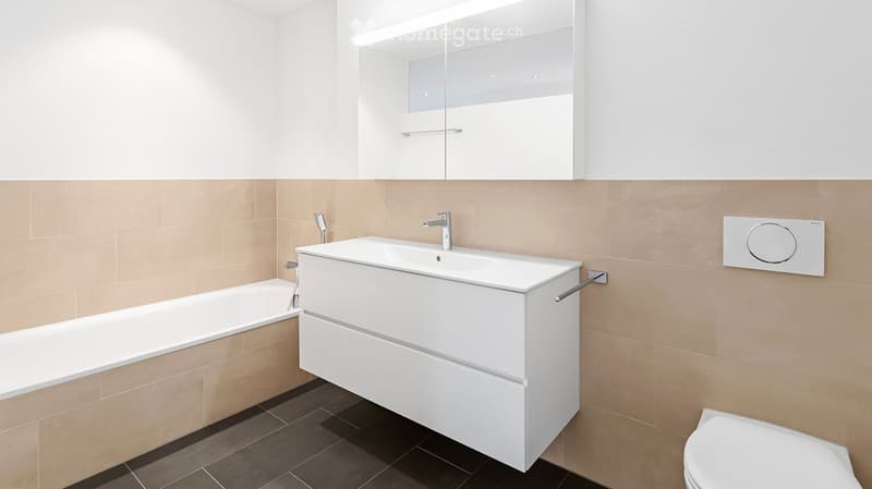 Bathroom. Modern bathroom with a white sink cabinet, bathtub, toilet, and large mirror with built-in lighting.