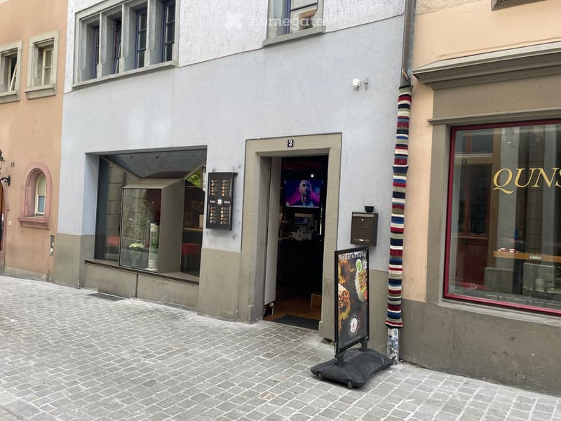 Facade of a building with a restaurant entrance, menu board, and a colorful striped pole.