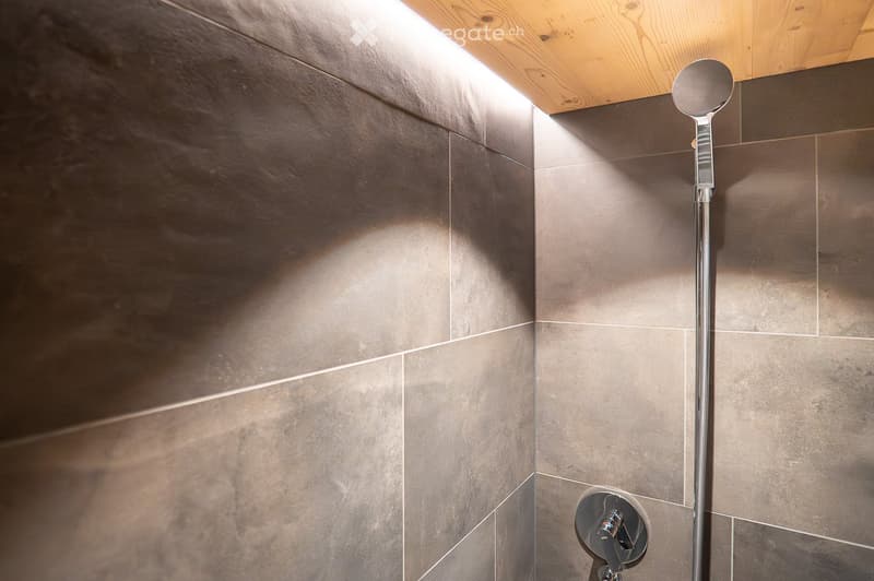 shower area with shower head and water handle, gray tiles, wooden ceiling