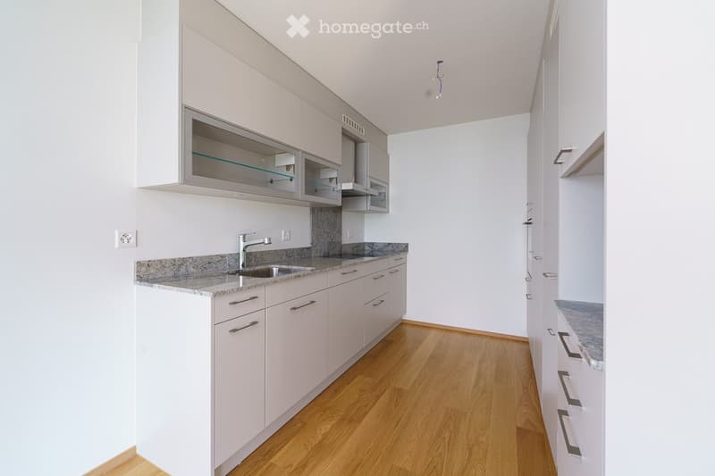 Modern kitchen with white cabinets, granite countertop, and wooden flooring.