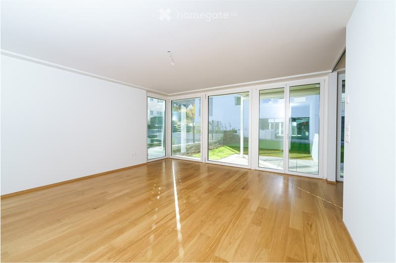Empty room with light wooden flooring and large glass sliding doors leading to an outdoor area.