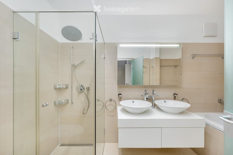 Modern bathroom with a glass-enclosed shower, double sink vanity, and a large mirror above the sinks.