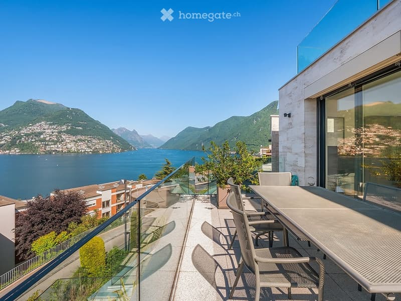 Balcony with a scenic lake and mountain view, equipped with a table and chairs.