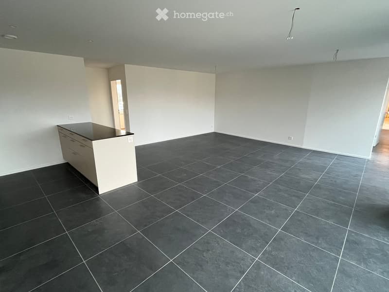 Empty room with white walls, black tiled floor, and a white kitchen island