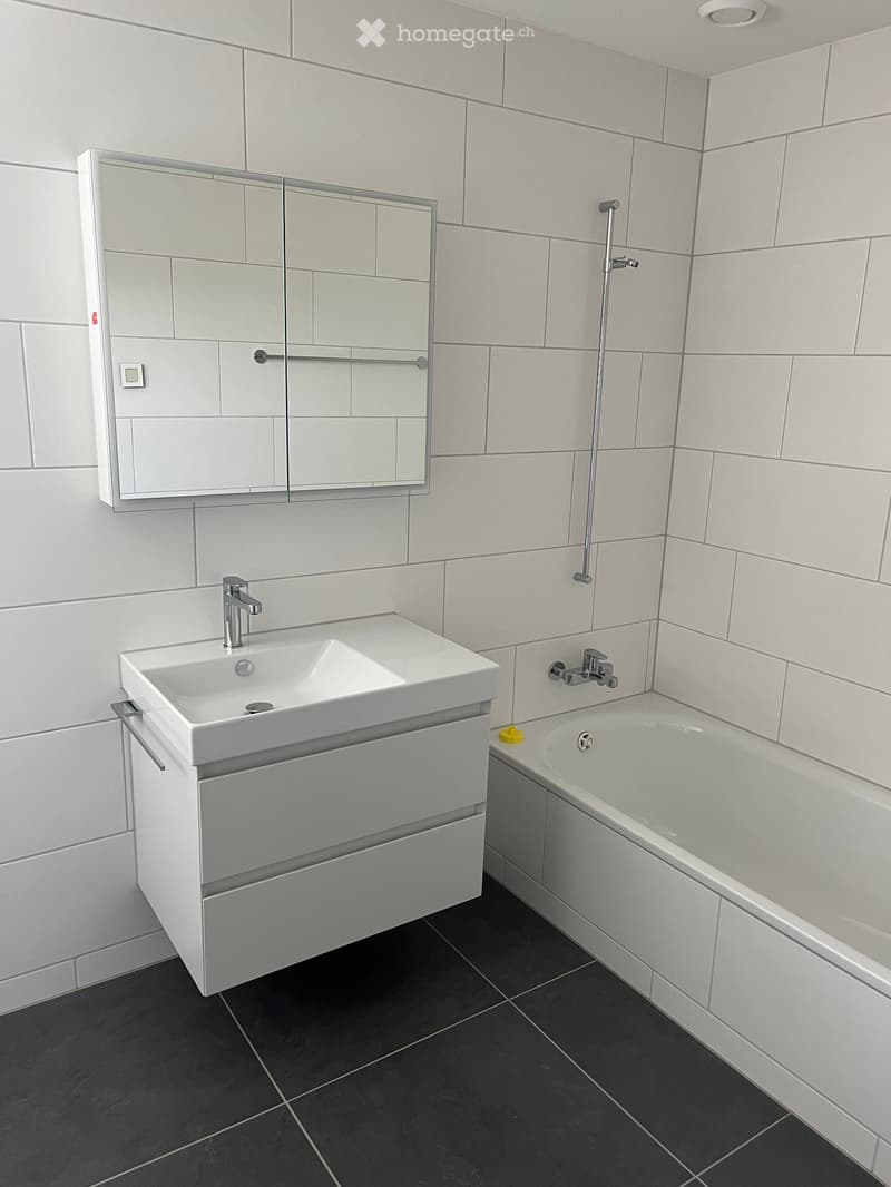 modern bathroom with white walls and floor, white bathtub, white vanity with a sink, chrome fixtures, and white tiled walls