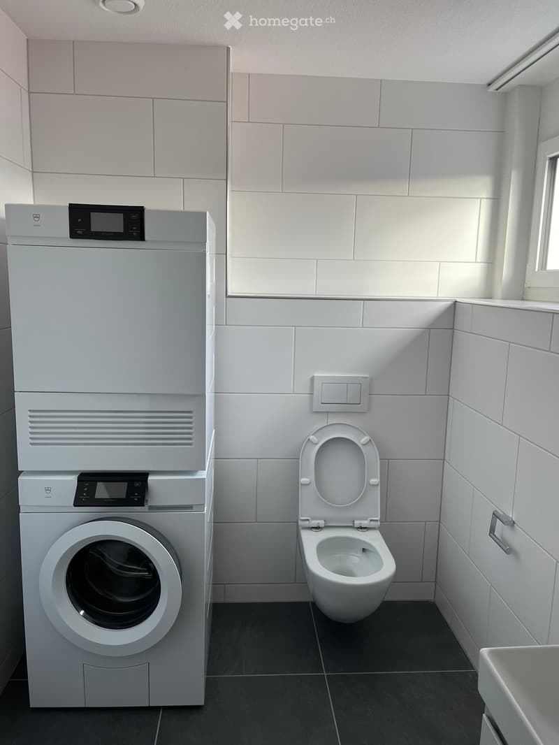 White tile walls, white tile flooring, washing machine, dishwasher, toilet, sink
