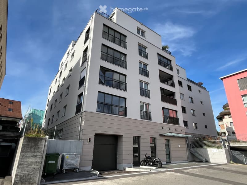 4-story building, balconies, garage entrance, staircase, trash bins, motorcycle parked in front