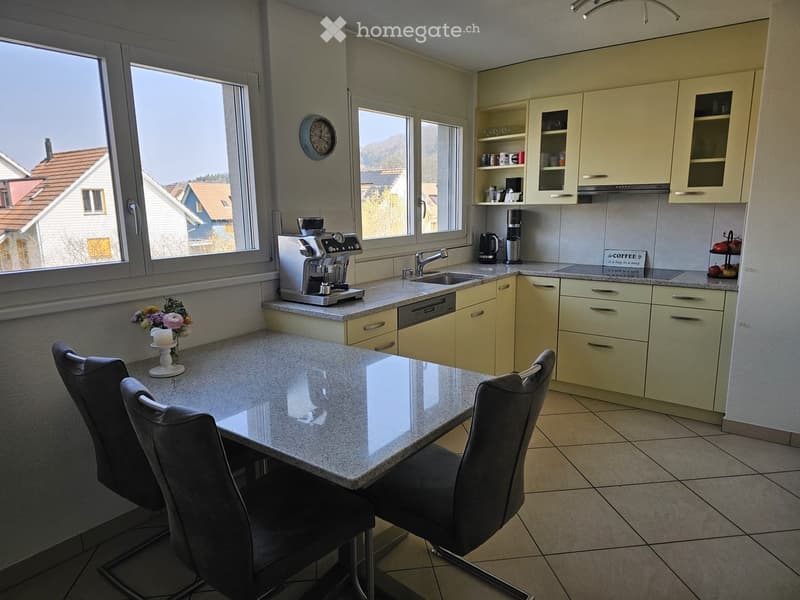 modern kitchen, granite countertop, 4 chairs, stainless steel appliances, dishwasher, dining table, natural light, windows, decorative clock, flowers