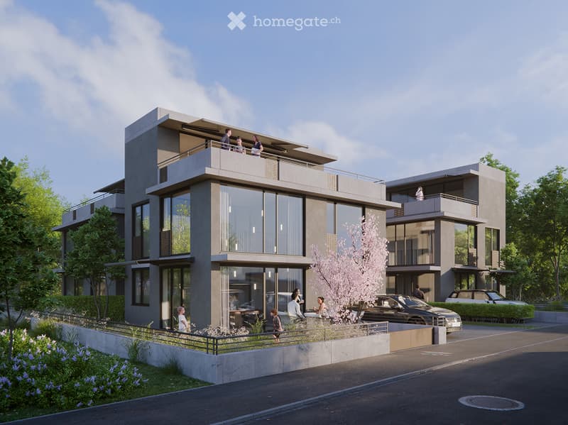 Modern two-story residential building with large glass windows, balconies, and contemporary design. The building is surrounded by greenery and has a parking area in front.