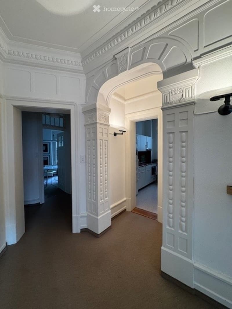 Empty hallway, white walls, decorative ceiling, floor, 2 doors leading to the kitchen and another room