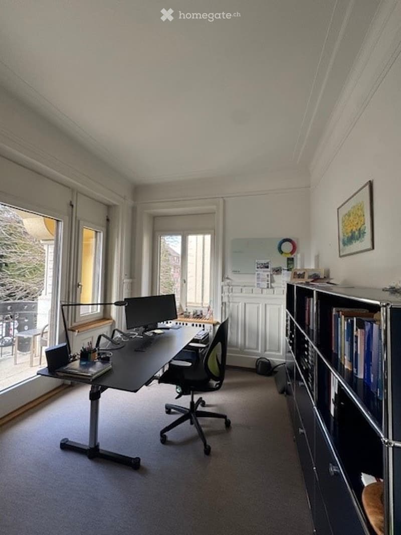 Office with a desk, chair, computer, books, picture frame, radiator, and windows