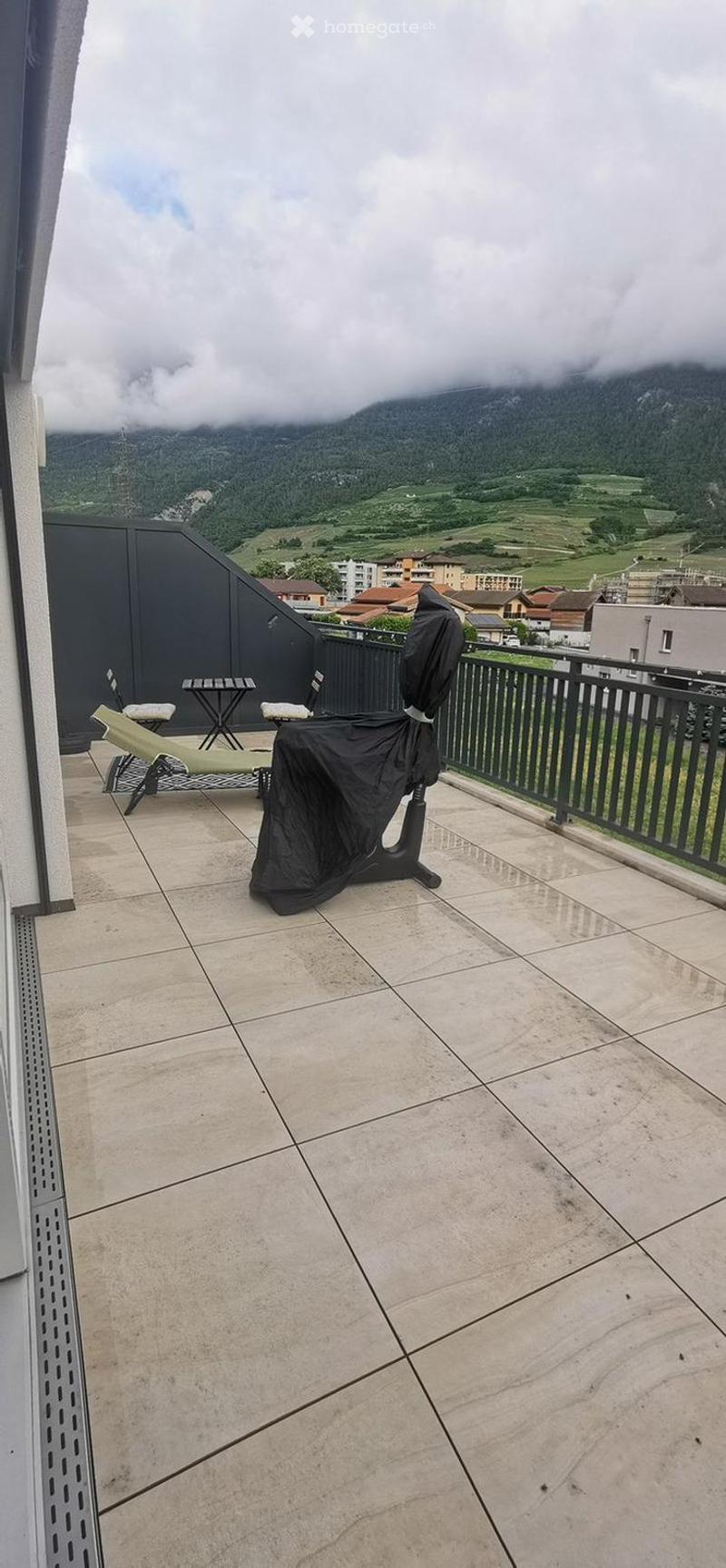 Balcony with tiled floor, lounge chair, small table, and scenic mountain view.