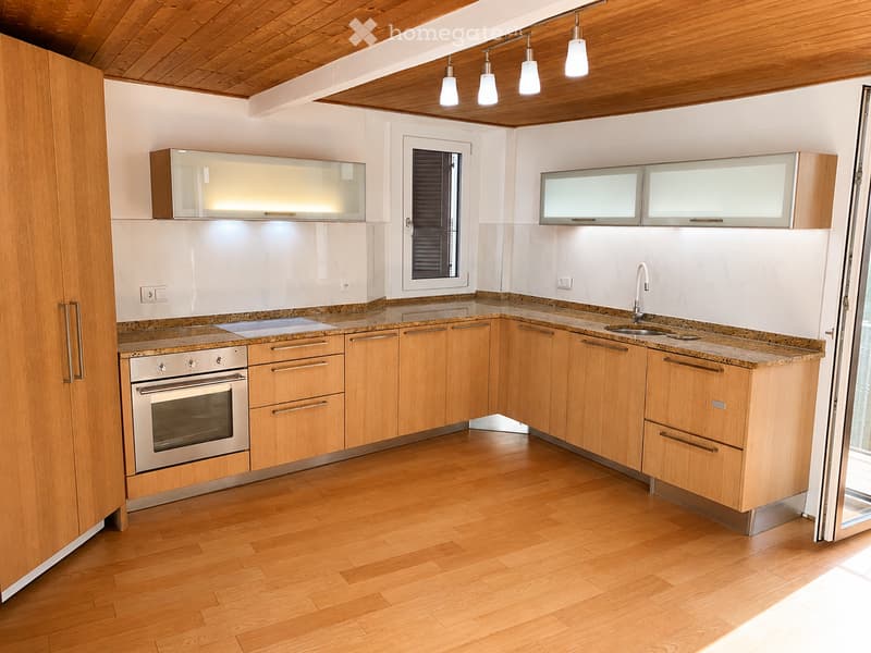 Modern kitchen with wooden cabinets, granite countertops, stainless steel oven, and a sink with a modern faucet.