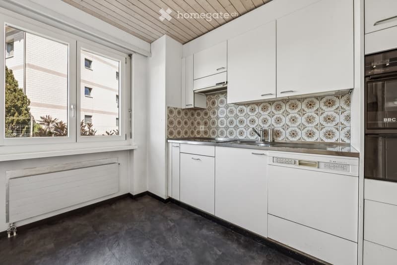 modern kitchen with white cabinets, tiled backsplash, stainless steel sink, dishwasher, and a window