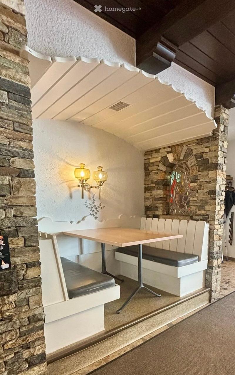 Cozy dining area with a wooden table, built-in bench seating, stone walls, and decorative wall-mounted lamps.