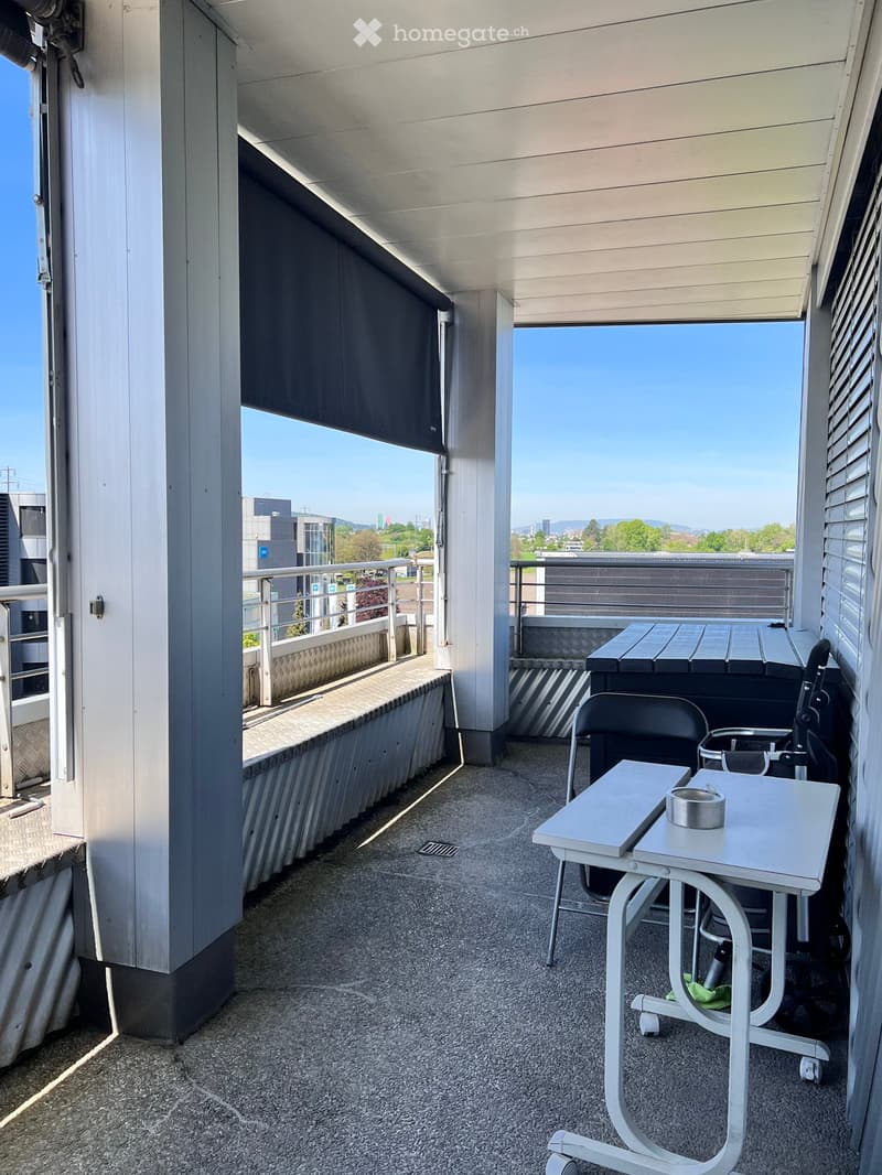 Balcony with metal railing, tables, chairs, black shade, view of the city
