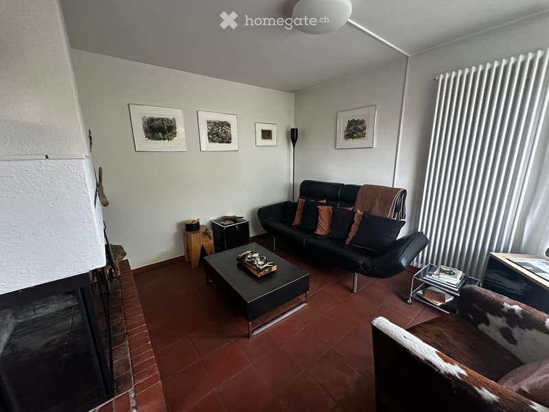 Modern living room with dark leather sofa, coffee table, side table, floor lamp, and artwork on the walls.