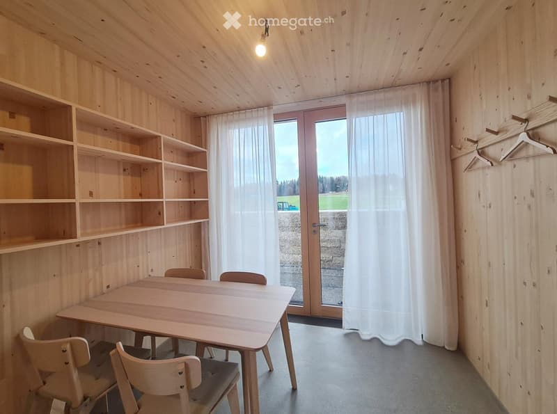 Wooden walls, built-in shelves, table, chairs, curtains, glass door, light fixture