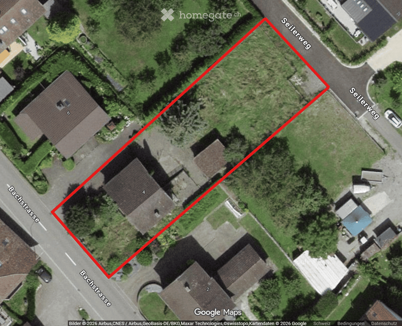Building. Aerial view of a residential area showing multiple houses with pitched roofs, surrounded by greenery and streets labeled Seilerweg and Bachstrasse.