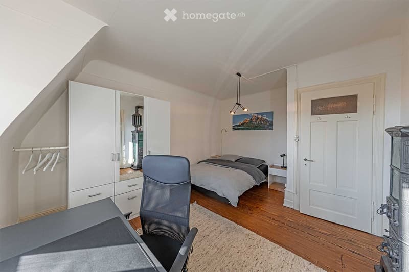 bedroom with bed, desk, chair, wardrobe, rug, lamp