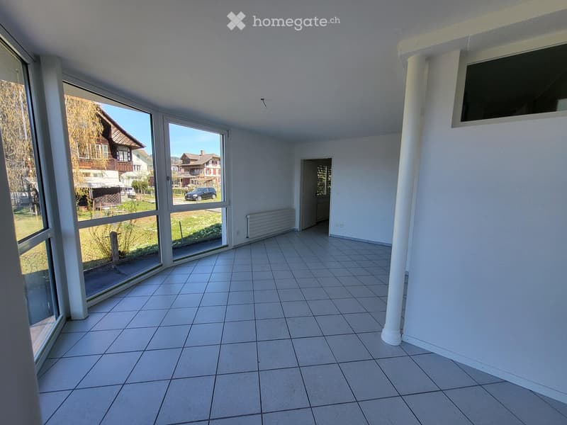 Empty room with tiled floor, large windows, white walls, and a radiator. No furniture or equipment present.