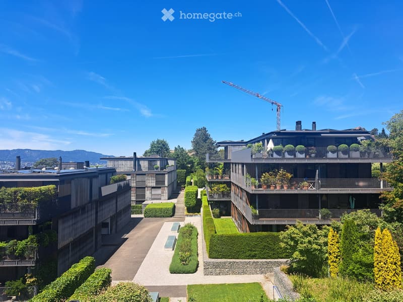 Modern residential complex with multiple buildings, balconies, greenery, and a well-maintained garden area.