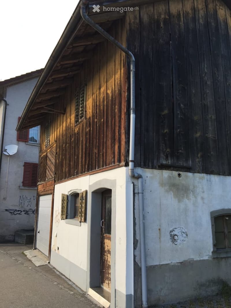 Old wooden house, white and brown walls, wooden door, windows with shutters, satellite dish, graffiti on the wall