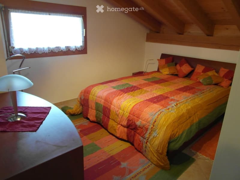 Bedroom with a bed, desk, lamp, rug, and window with curtains