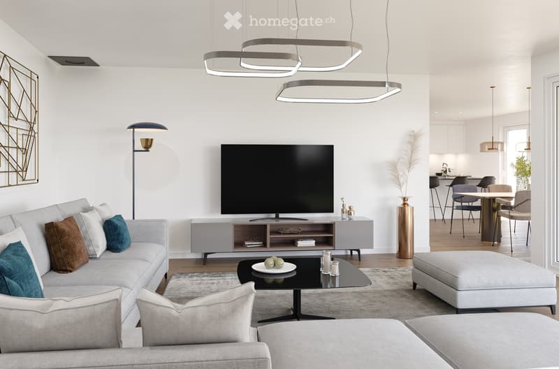 Modern living room with a grey sectional sofa, coffee table, ottoman, television, floor lamp, and a dining area with a table and chairs.