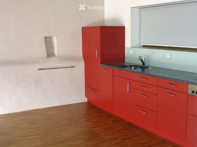 Empty room with red cabinets, a sink, and a wooden floor. No furniture or personal items are present.