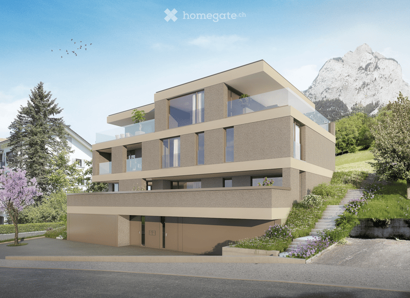 Modern two-story house with beige and brown facade, large windows, balconies, and a garage. Surrounded by greenery and a scenic mountain backdrop.