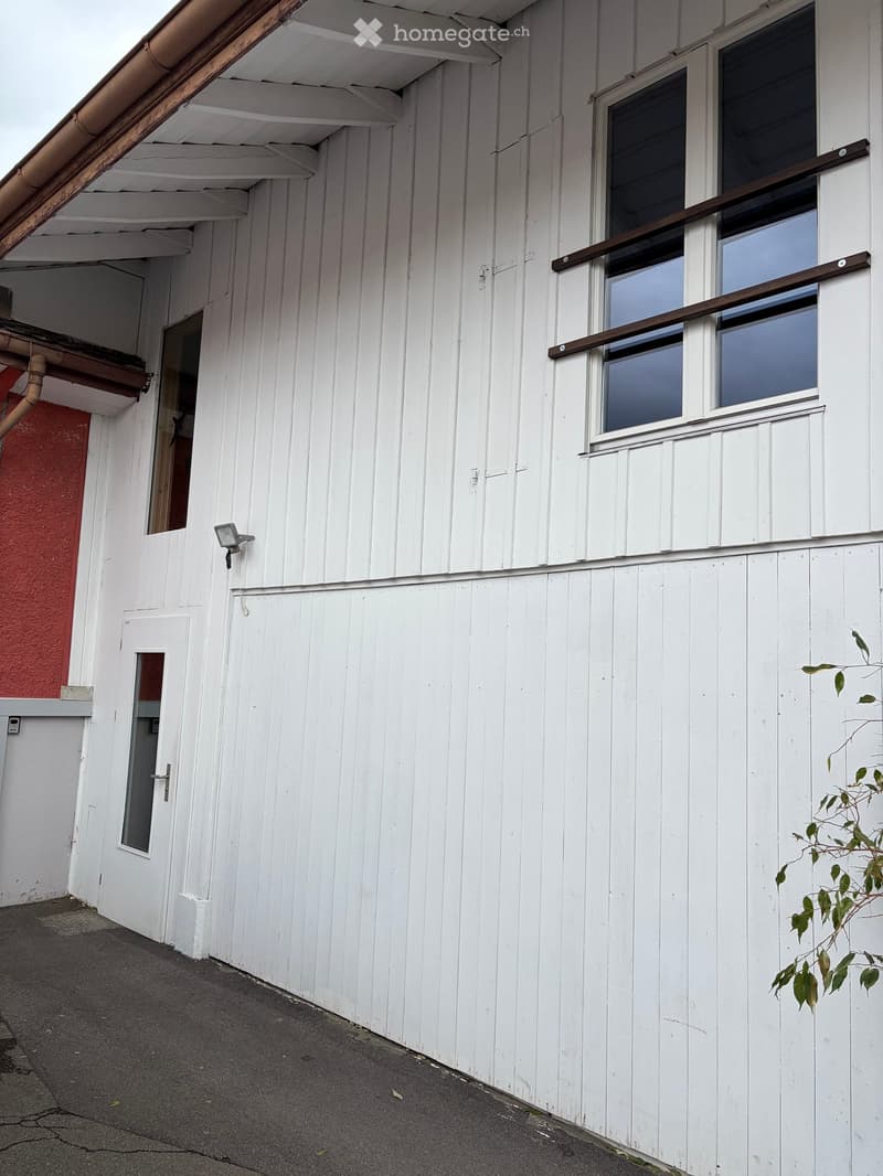 White wooden building exterior with a window, door, and small balcony railing.