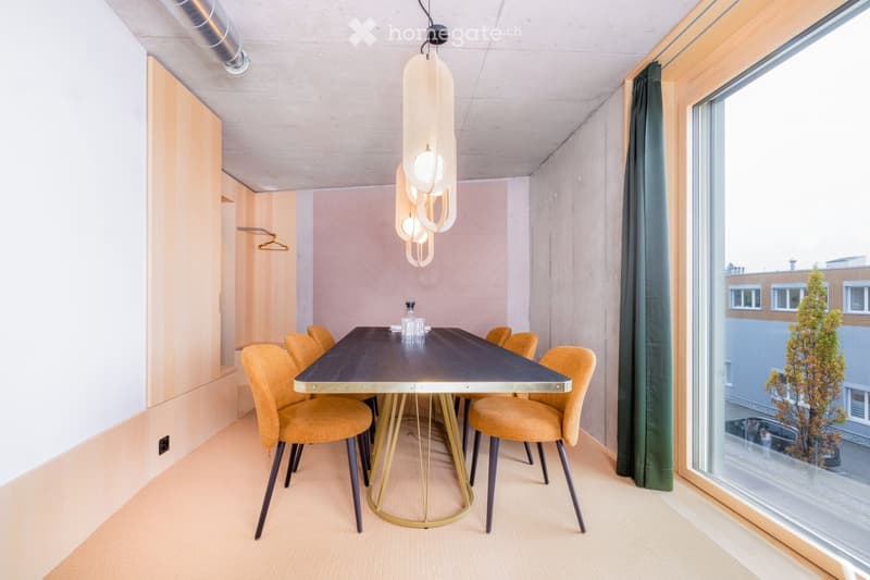 Modern dining area with a dark wooden table, six yellow chairs, a pendant light fixture, and a vase on the table. Large windows offer a view of the outside.