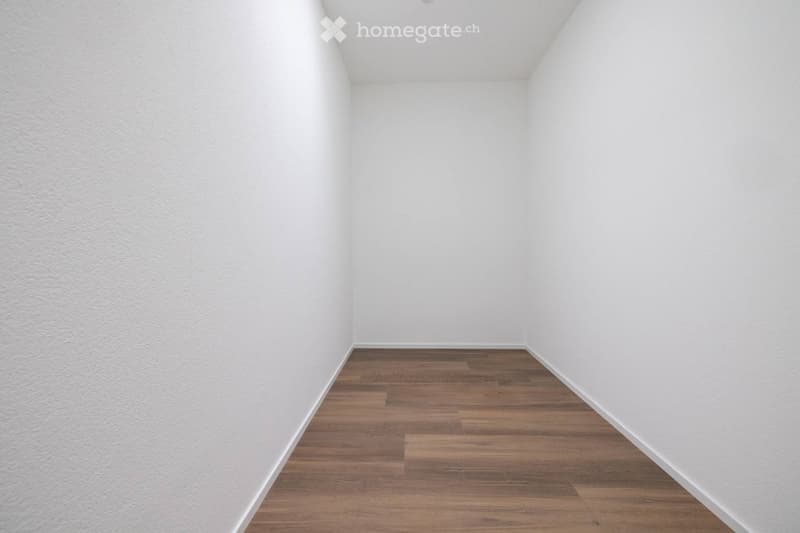 Completely empty room with white walls and wooden floor. No furniture or equipment.