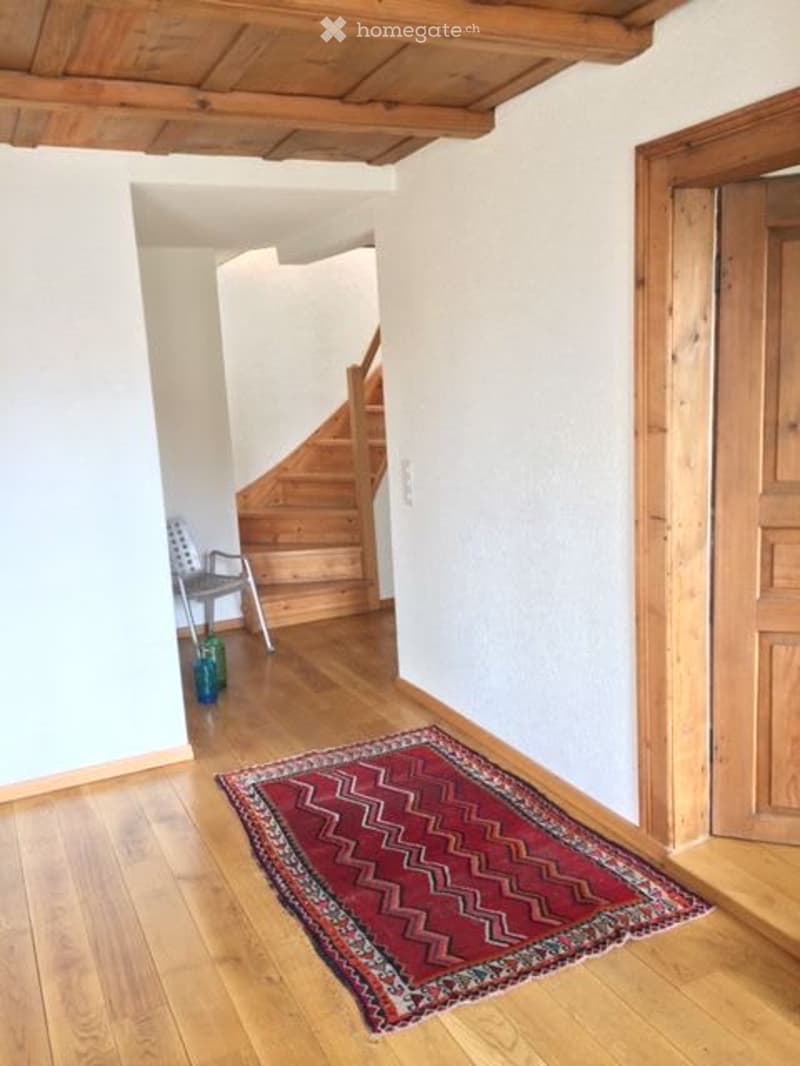 wooden flooring, white walls, wooden door, wooden stairs, chair, rug, blue objects