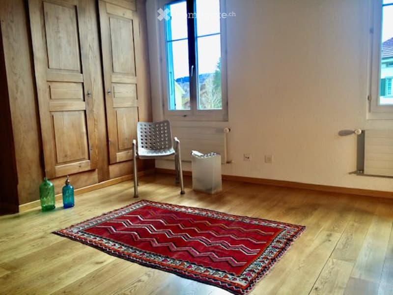 Wooden floors, large rug, wooden wardrobe, chair, 2 windows