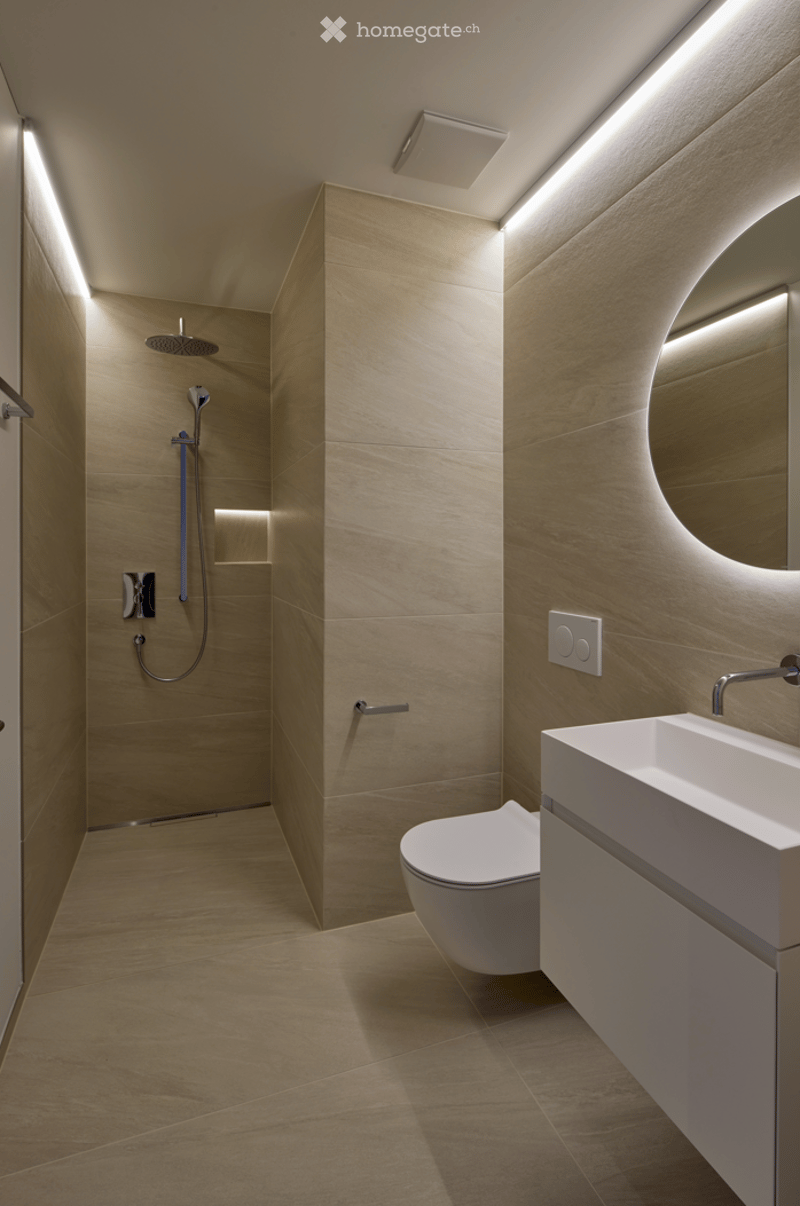 Minimalist bathroom with beige tiles, shower, toilet, sink, mirror, and lighting