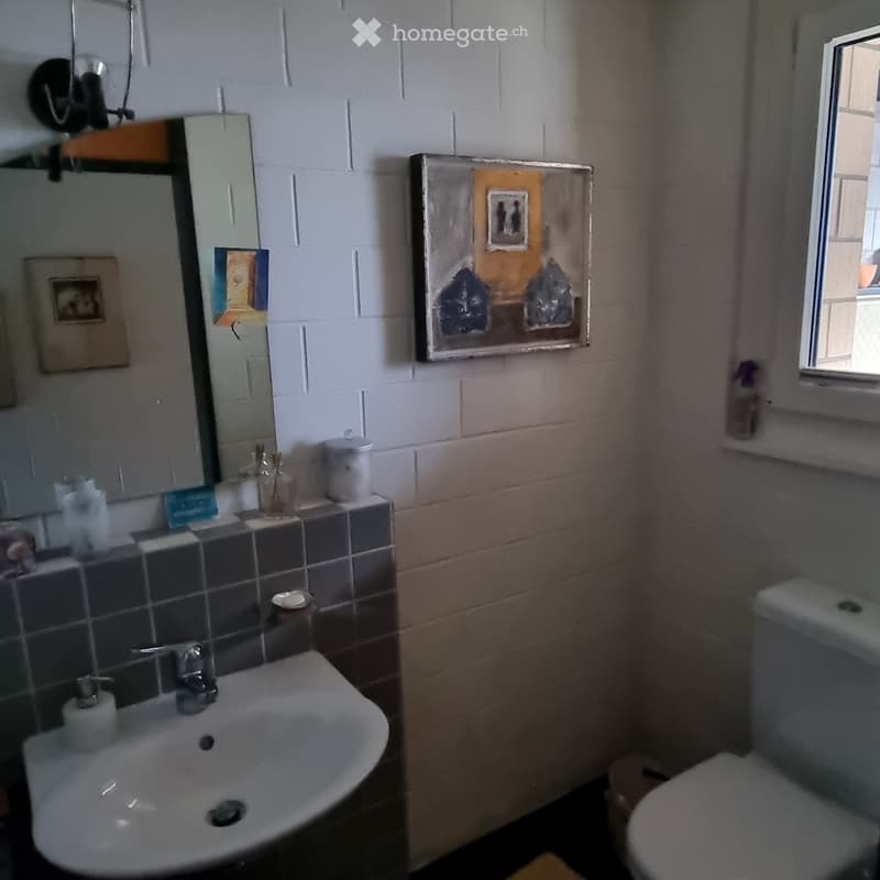 Bathroom with sink, mirror, toilet, and window