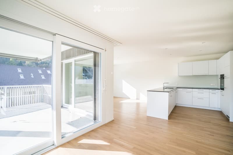 Modern, minimalist kitchen with white cabinets, a central island, and a large glass sliding door leading to a balcony.