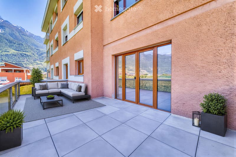 Balcony with a modern sofa, coffee table, and candle, overlooking a scenic mountain view.