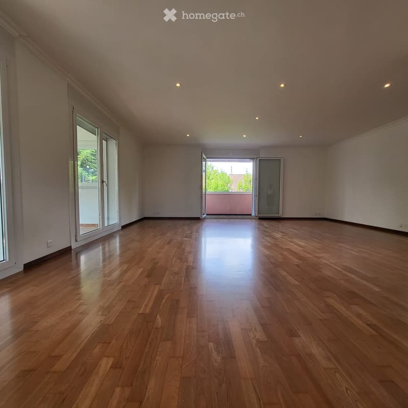Empty room with wooden flooring, large windows, and recessed lighting. No furniture or equipment present.