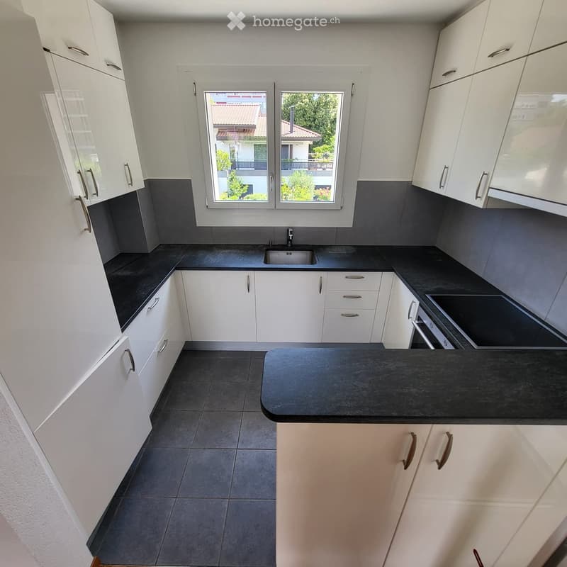 Modern kitchen with white cabinets, black countertops, and a central island. Features a sink, faucet, and ample storage space.