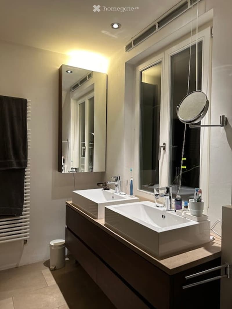 modern bathroom with two sinks, large mirror, and a window