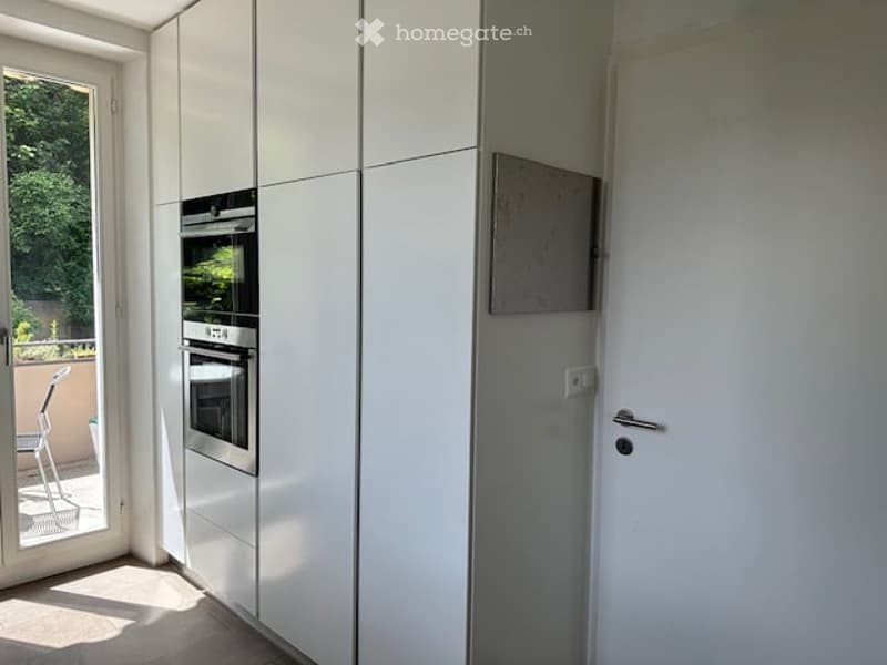 modern kitchen with white cabinets, stainless steel oven, glass door, balcony view