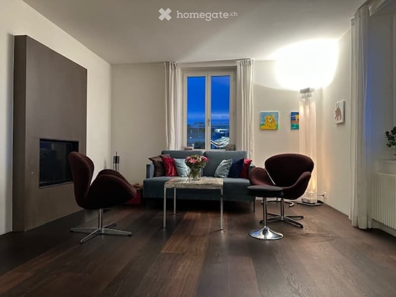 modern living room with fireplace, blue couch, wooden floor, center table, chairs, paintings on the wall