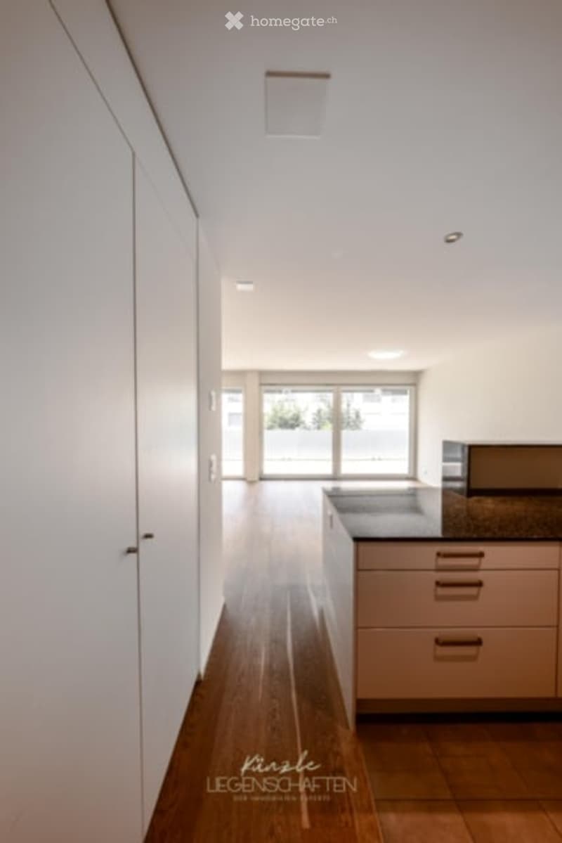Empty room with white walls, wooden floor, and large sliding glass door leading to a balcony.