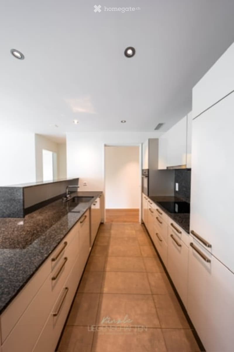 Modern kitchen with light-colored cabinets, granite countertop, and stainless steel appliances.